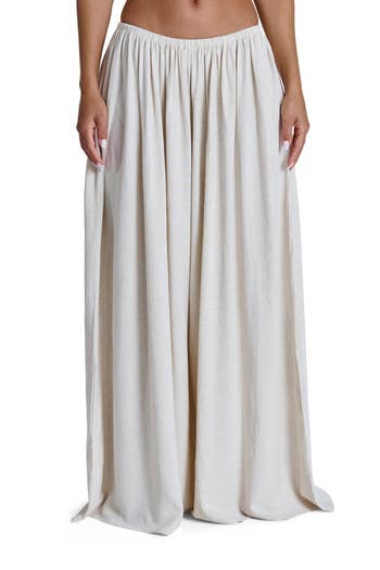A person wears a flowing, ankle-length skirt with a gathered waist, suitable for a relaxed, stylish look