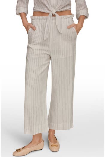 Woman wearing pinstriped wide-leg pants with a tied top, hands in pockets