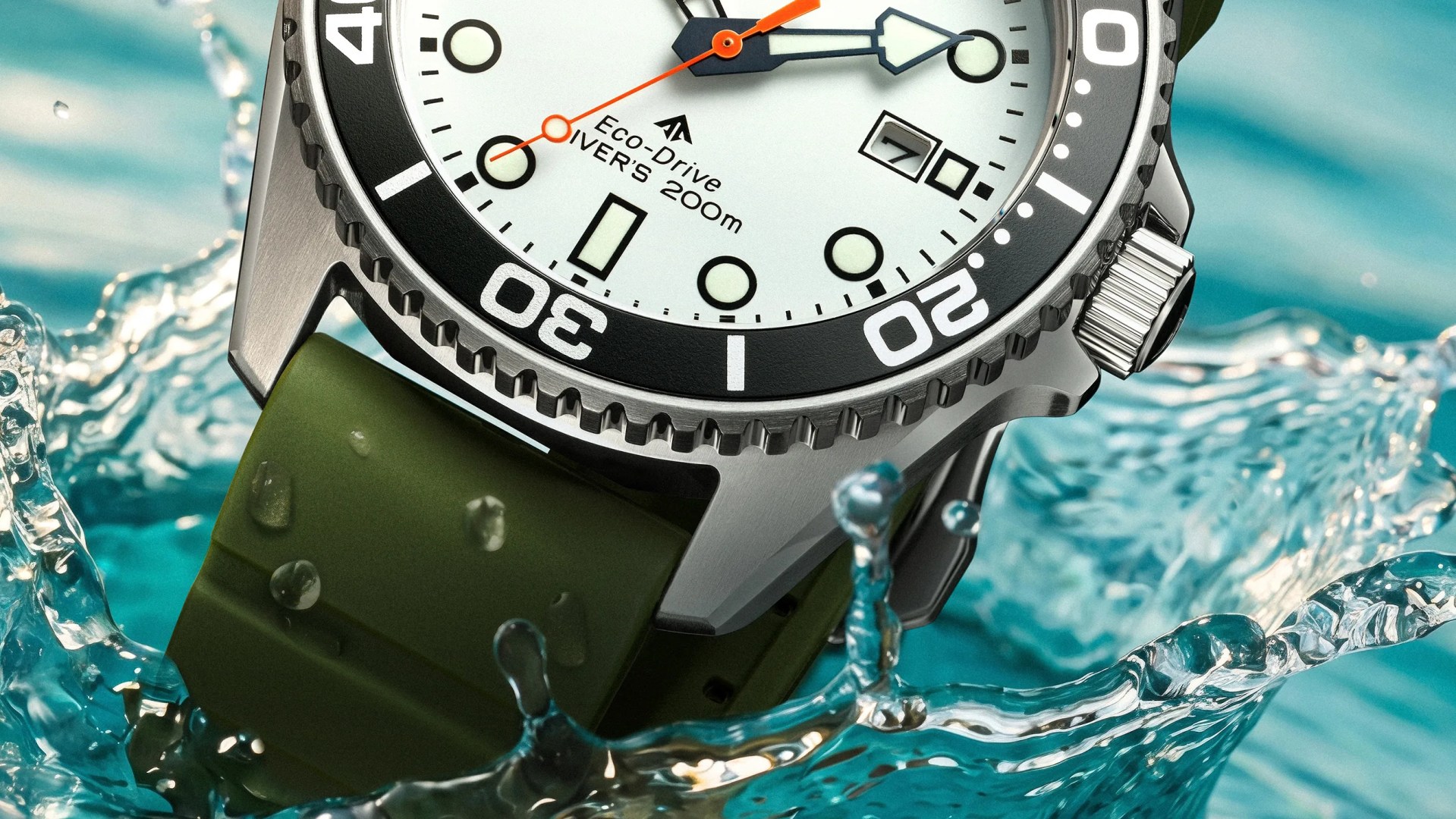 Close-up of a stainless steel diver's watch with a white dial, black bezel, orange second hand, and green rubber strap splashing in water.