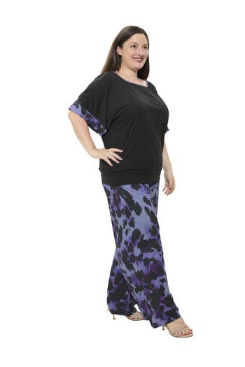 Person in a stylish black top with patterned pants, standing confidently. Fashionable look for a casual shopping outing