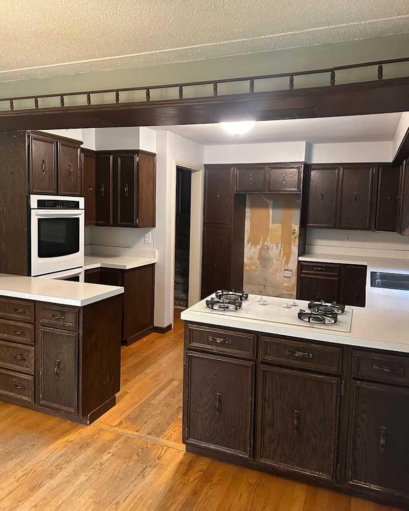 Spacious kitchen with dark wood cabinets, white countertops, a gas stove, and hardwood flooring.