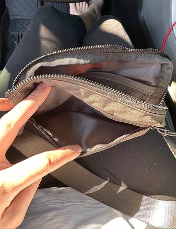 Reviewer opening the fanny pack to show pockets on teh inside