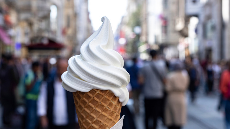 Soft serve ice cream from a fast food restaurant wit people in the background