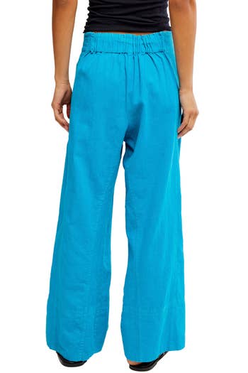 Person wearing loose, blue wide-leg pants, viewed from the back