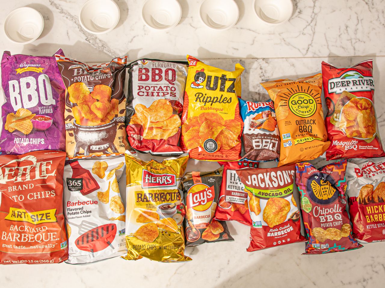 An assortment of different barbequeflavored potato chip bags arranged on a marble surface
