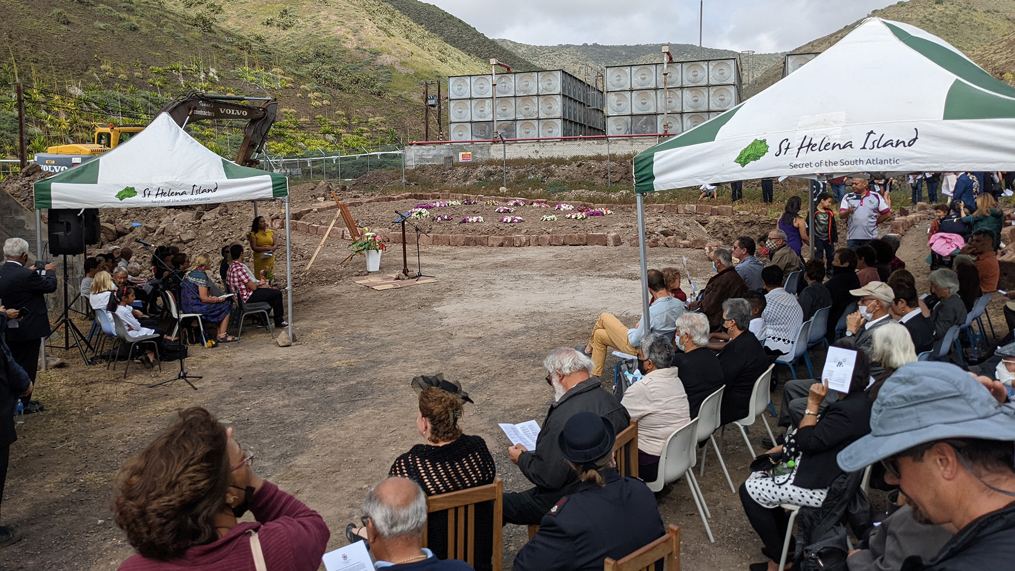 A series of people sit in chairs in a clearing