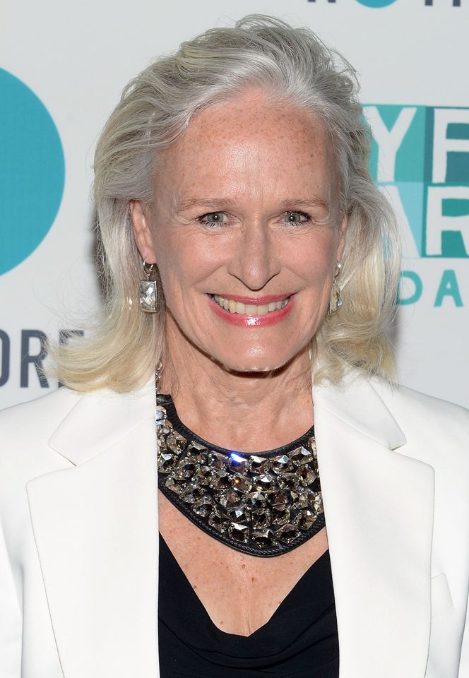 Glenn Close smiling at an event wearing a white jacket and necklace