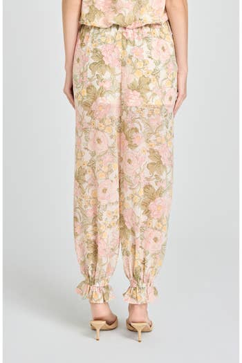 Person standing in floral-patterned, loose-fitting pants with ruffled cuffs, paired with heeled footwear. Fashion focus on comfortable, stylish attire