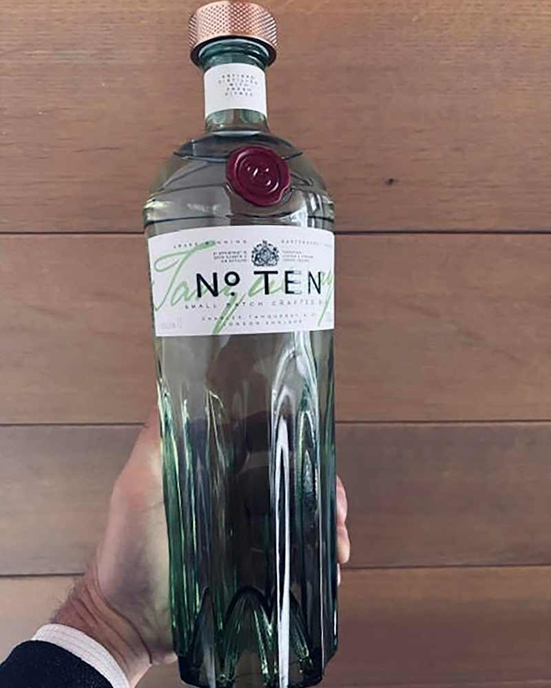 Someone holding bottle of Tanqueray 10 gin.