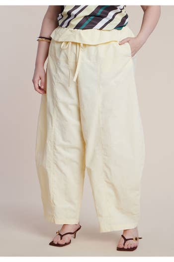Person wearing wide-legged, drawstring pants paired with an abstract striped top and sandals. Clothing style is casual and relaxed