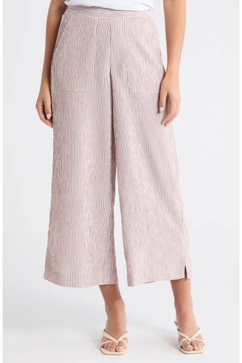 Woman wearing high-waisted, wide-leg striped pants and open-toe sandals. Perfect for a casual daytime look