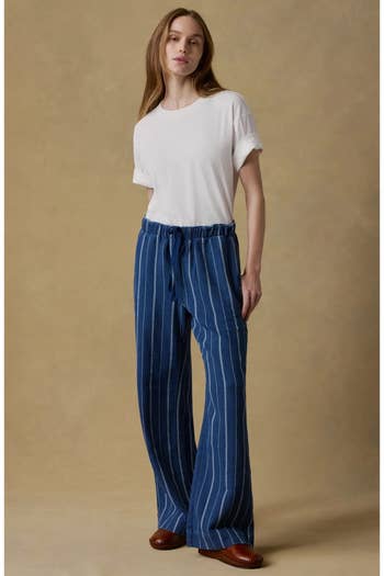 Person wearing a white t-shirt with relaxed-fit, striped pants and brown shoes, showcasing comfortable casual wear