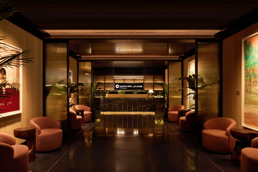 Entrance to the Chase Sapphire lounge at DFW airport with rose-colored armchairs against the walls and a check-in desk at the back of the entryway