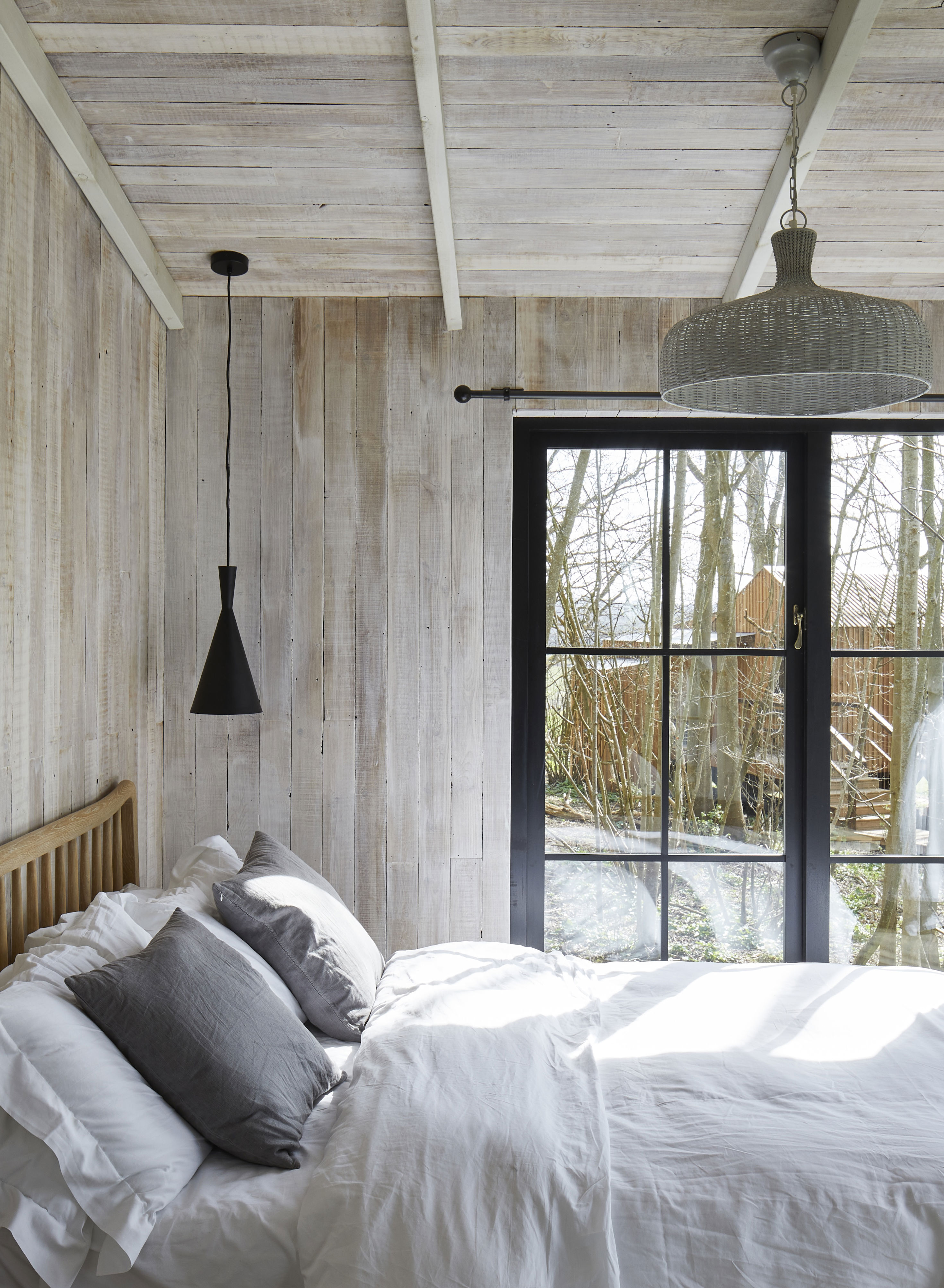 A contemporary bedroom clad in pale grey-toned wooden boards