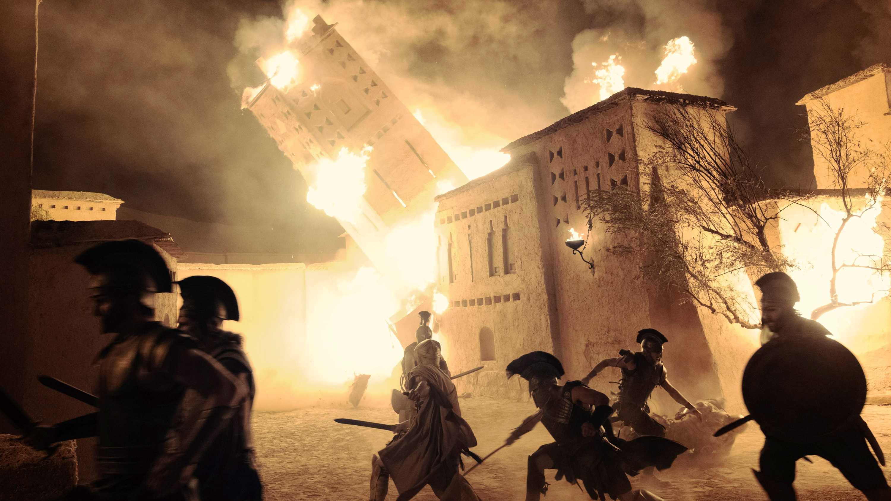 A burning building falls during the sacking of Troy in The Odyssey