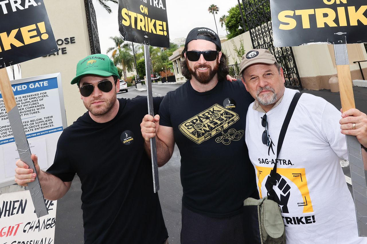 Jason Alexander with two other individuals holding On Strike signs during an event