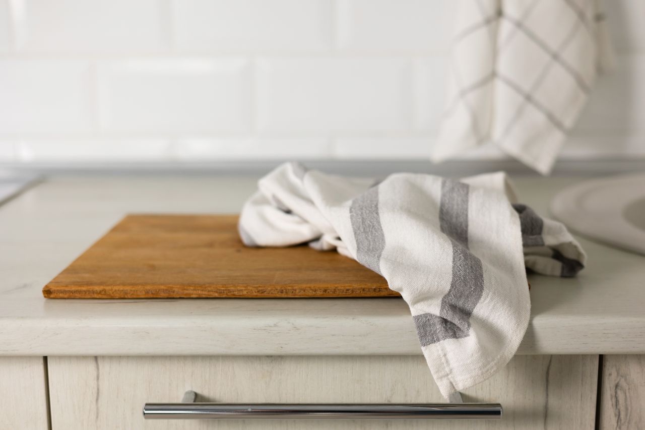 Kitchen counter with a wooden cutting board and a dish towel draped over it