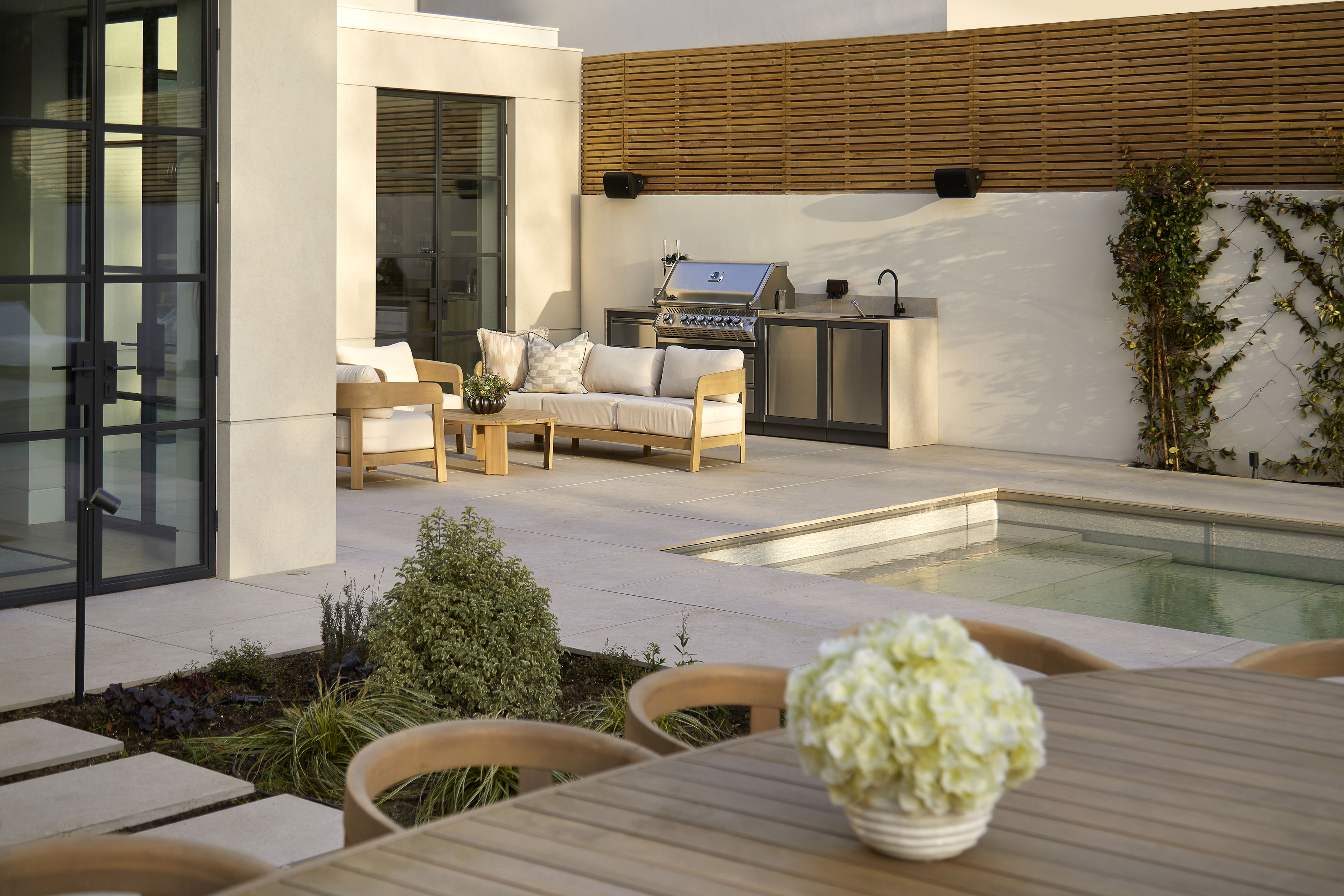 beautiful garden with an outdoor kitchen, dining area, lounge, and a retractable, sinking swimming pool