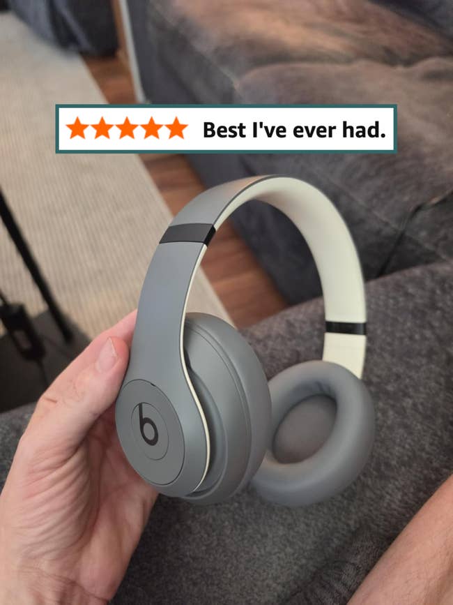 Person holding a pair of sleek, over-ear Beats headphones, suitable for music enthusiasts and shoppers interested in audio gear