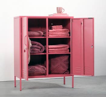 Metal locker cabinet with textured blankets and a mug on top, ideal for organizing and adding style to a room