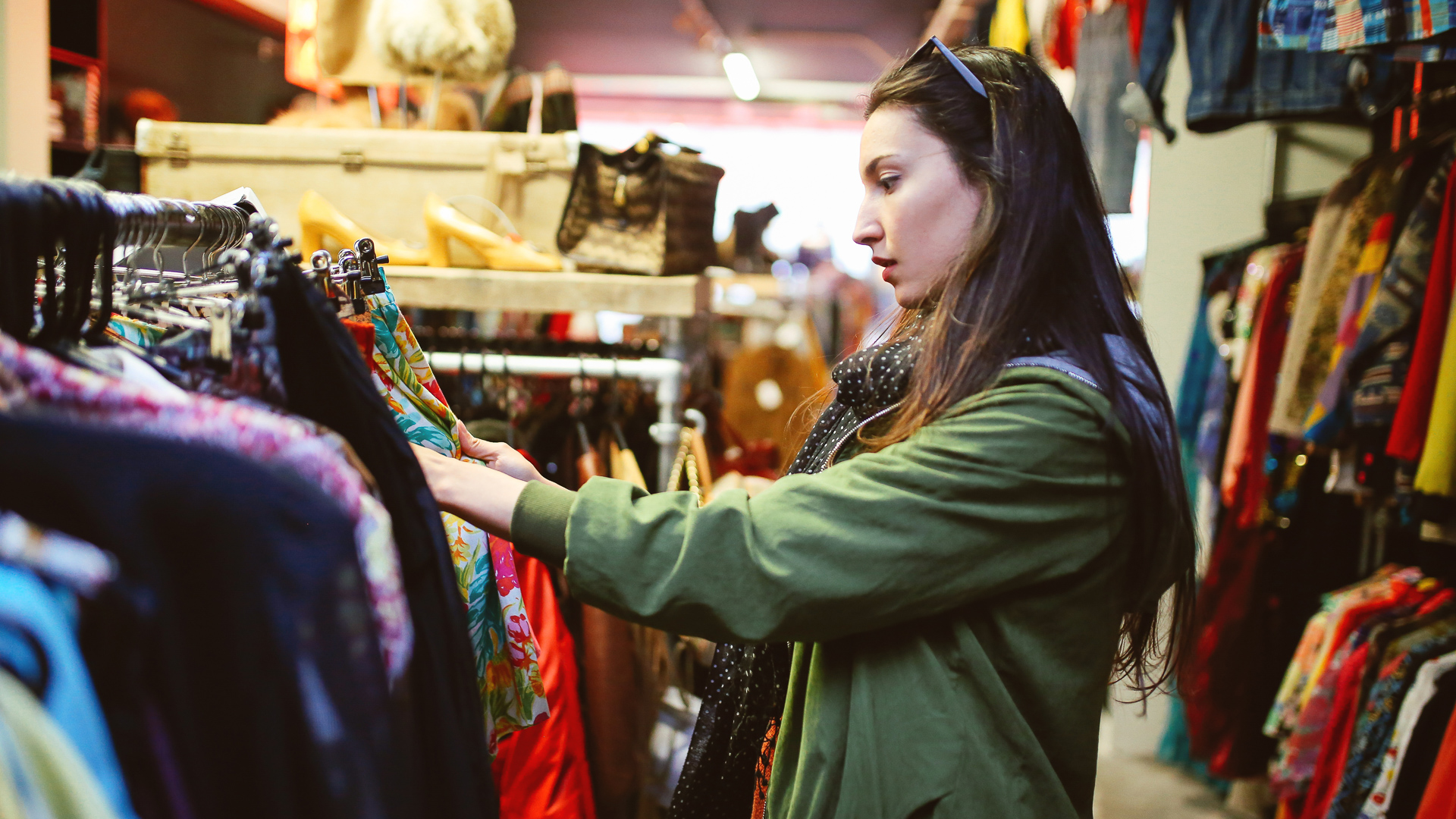 Discover the joy of browsing vibrant vintage clothing racks as someone explores unique patterns and accessories in a shop