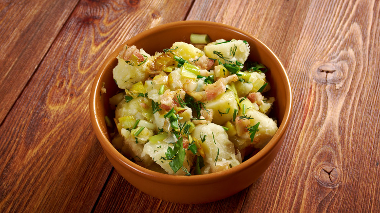 A wooden bowl filled with warm German potato salad
