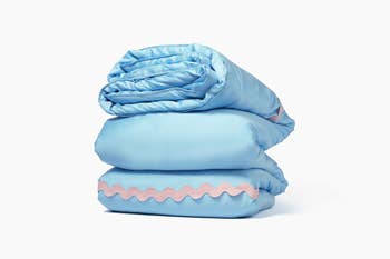 Stacked light blue comforters with pink trim, showcasing soft bedding products