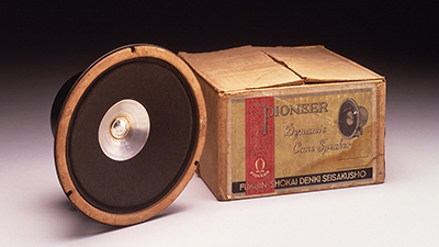 An old Pioneer speaker driver and its box photographed on a white table