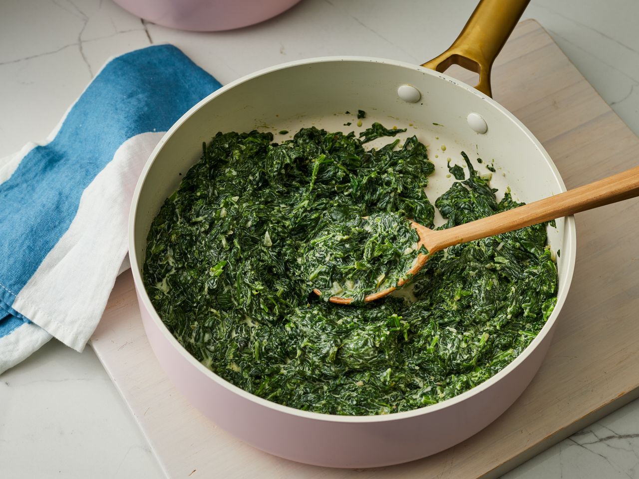 high angle looking at a pan of creamed spinach with a spoonful resting in the pan