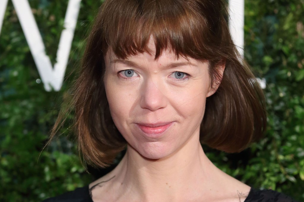Portrait of a woman with short brown hair and blue eyes, smiling faintly.