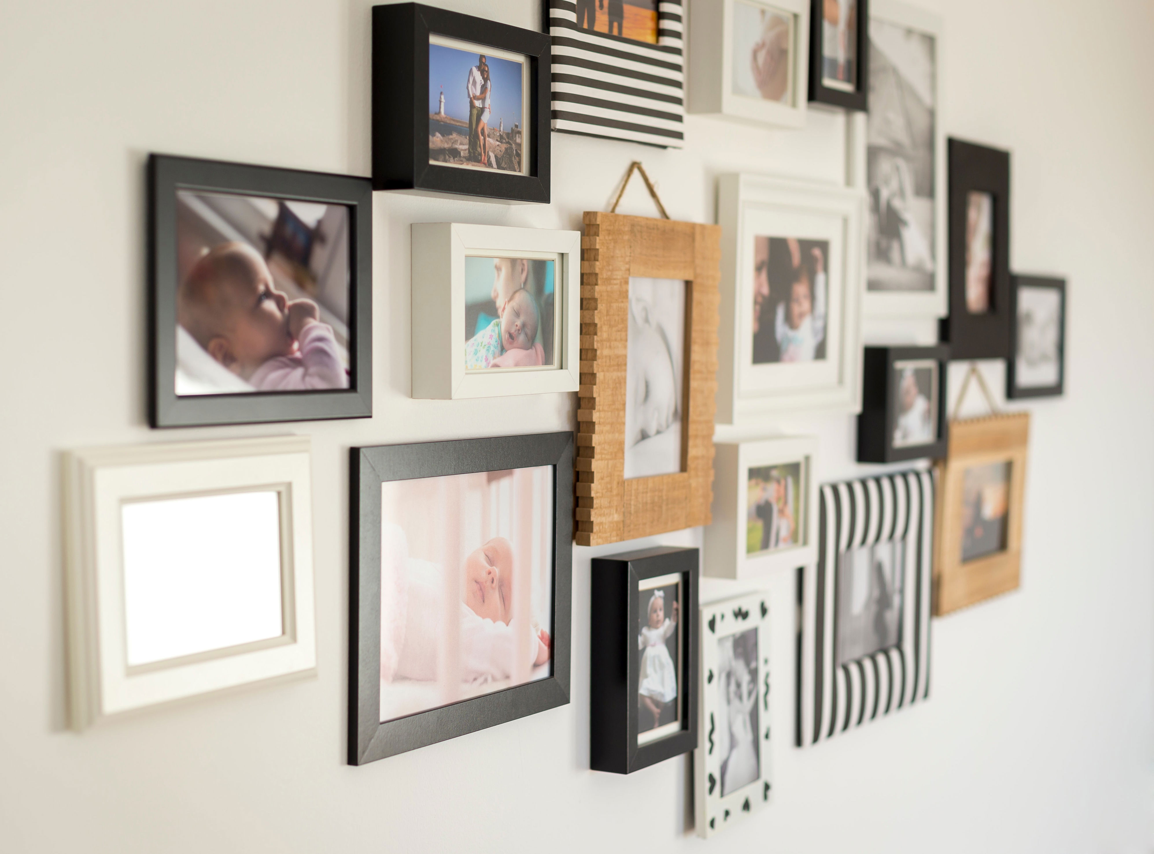 A collage of various baby and family photos in assorted frames on a wall
