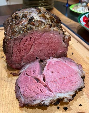 Sliced roast beef on a wooden board, showcasing its juicy, tender interior and seasoned crust. Ideal for a gourmet meal