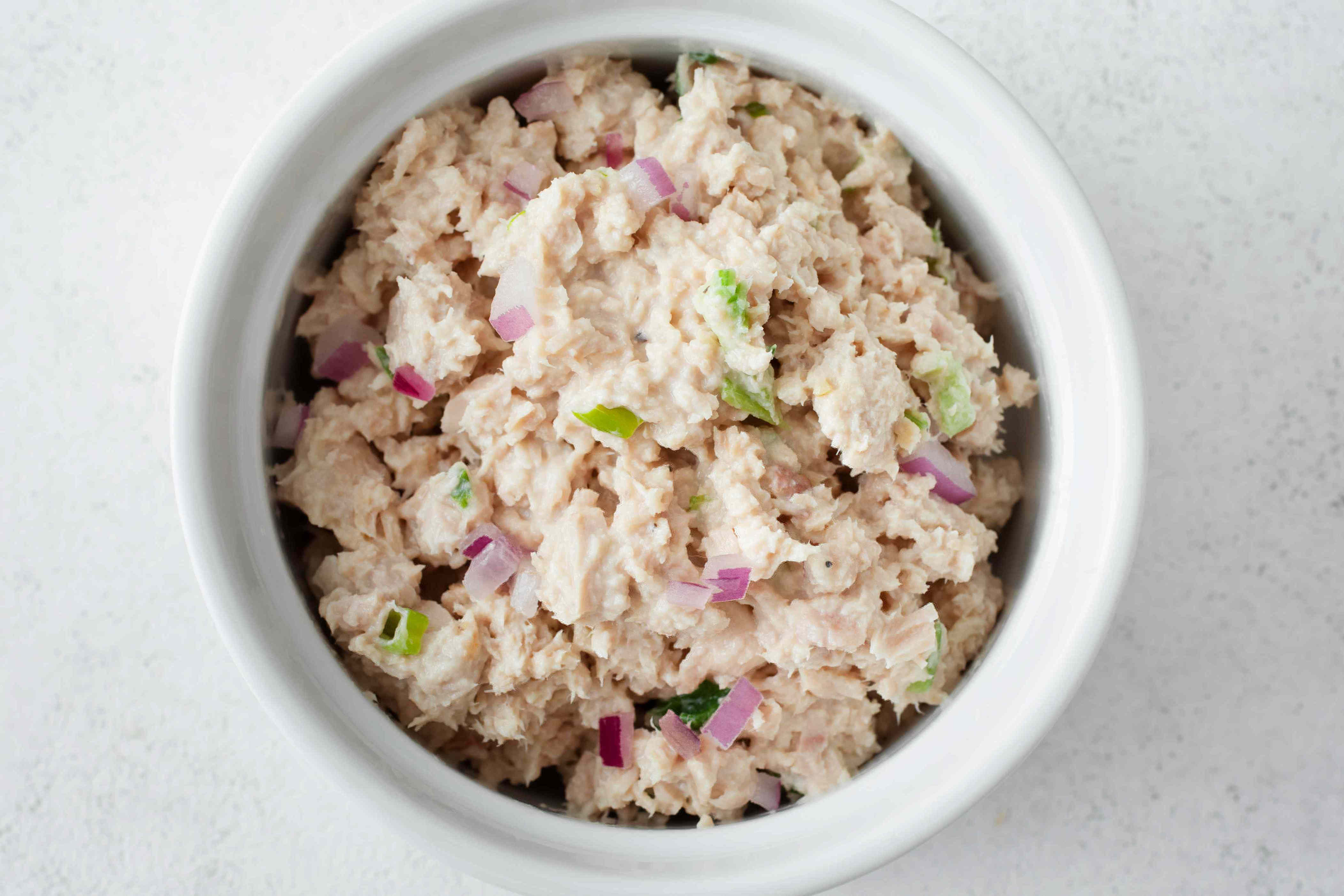 Bowl of tuna salad mixed with chopped onions and green vegetables