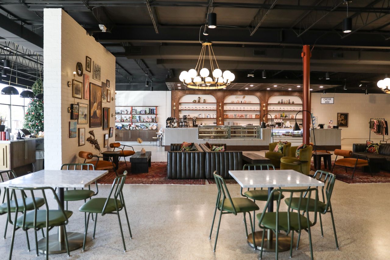 A modern caf interior with tables chairs and a counter with shelves in the background featuring a chandelier and cozy decor