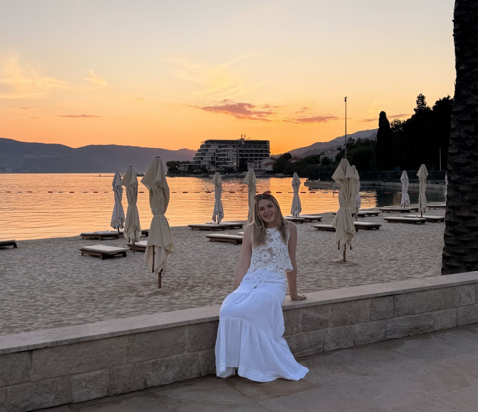Alice Giddings smiling in front of the water and sunset