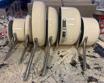 A set of stacked nonstick pans with stainless steel handles on a kitchen countertop