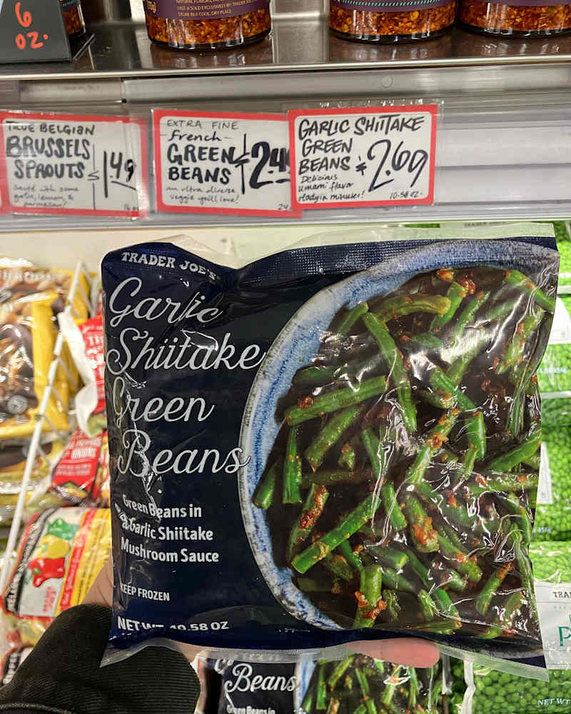 Someone holding package of Trader Joe's garlic shiiitake green beans.