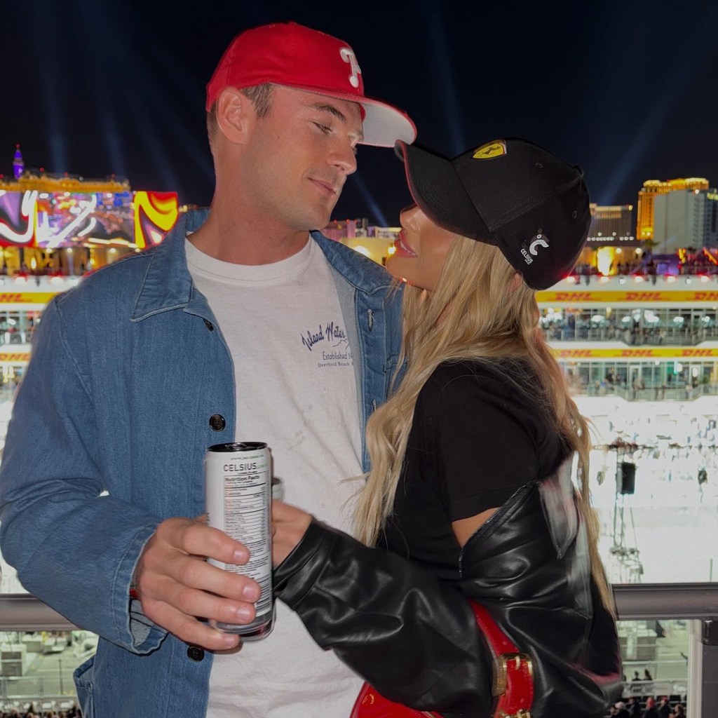 Paige Lorenze and Tommy Paul looking at each other, wearing hats, with city lights in the background.