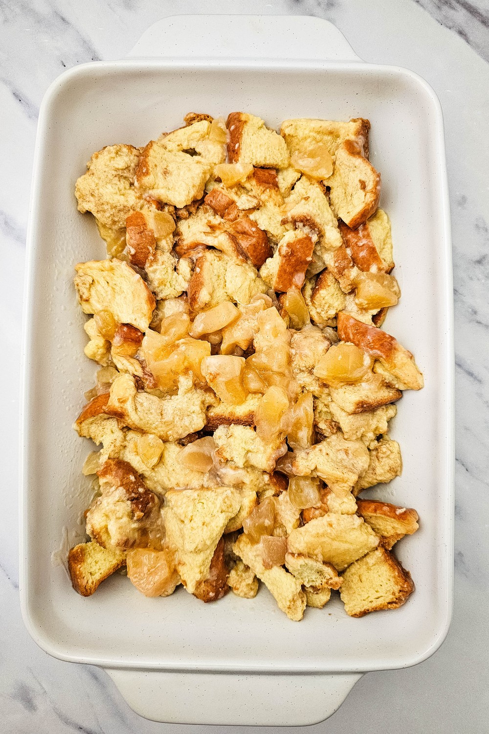 Apple pie bread pudding in a white 9x13 baking dish ready for the oven