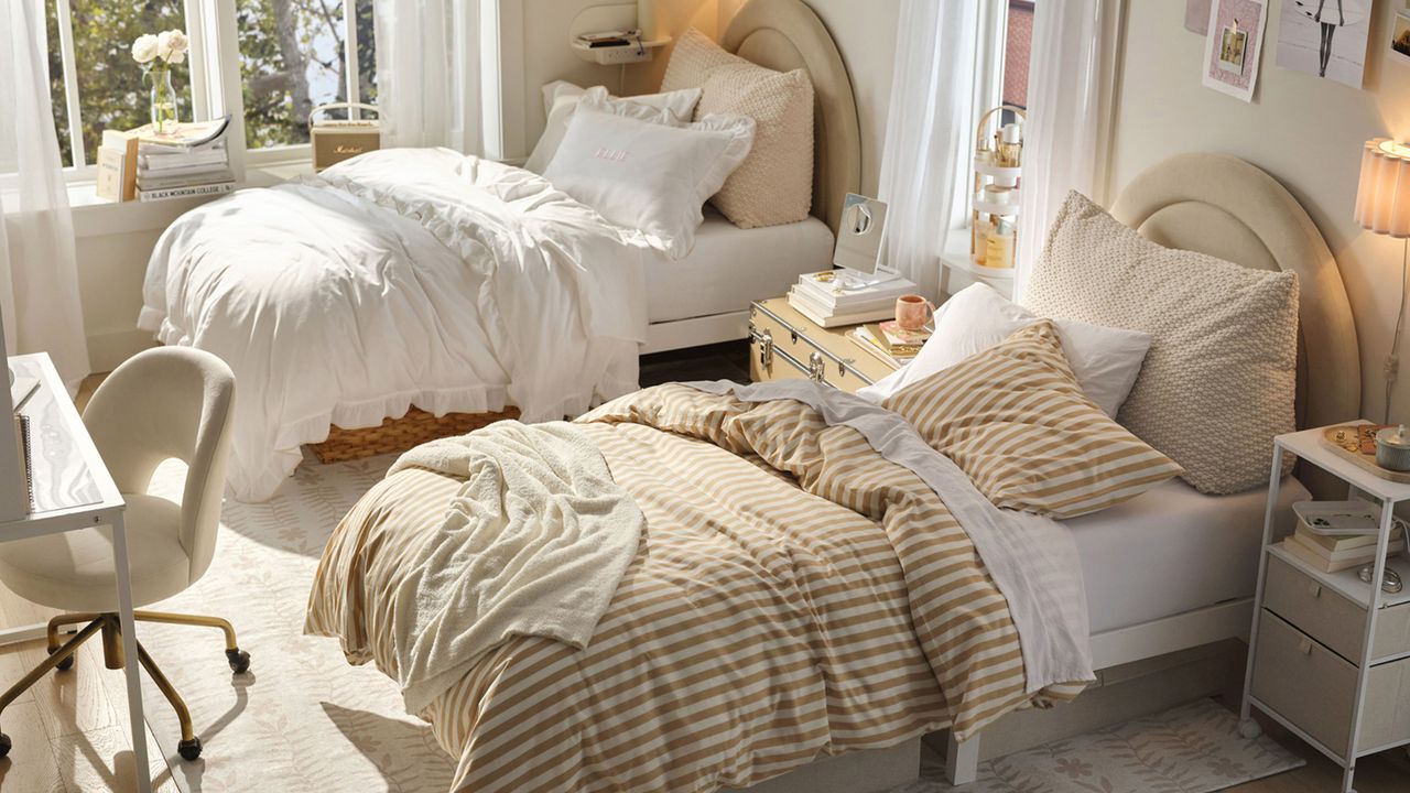 Stylish neutral dorm room with striped and ruffled bedding, matching arched headboards, and clever storage scattered throughout