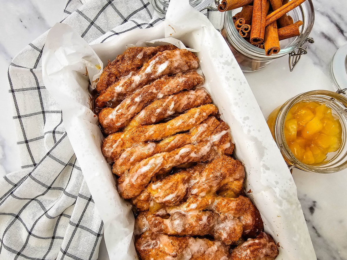 Glazed apple cinnamon biscuit loaf in a parchment lined bread pan
