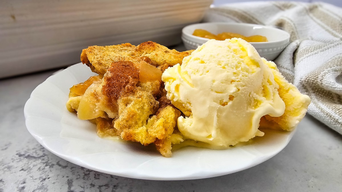 Closeup of warm apple pie bread pudding with melting vanilla ice cream