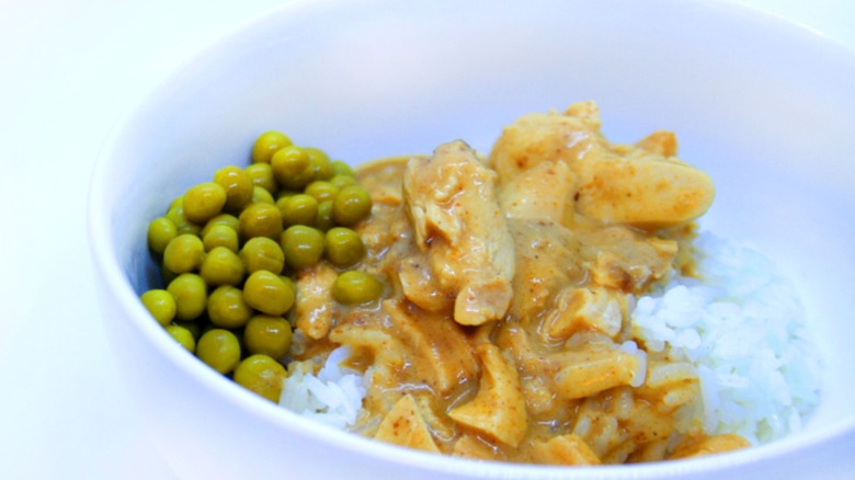 Chicken paprikash with rice and peas in white bowl
