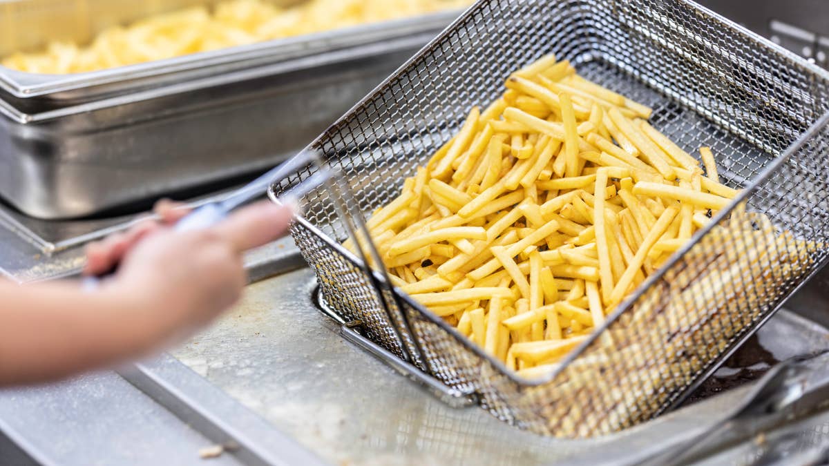 female-hands-holding-a-frying-pan-with-french-fries-at-a-commercial-kitchen