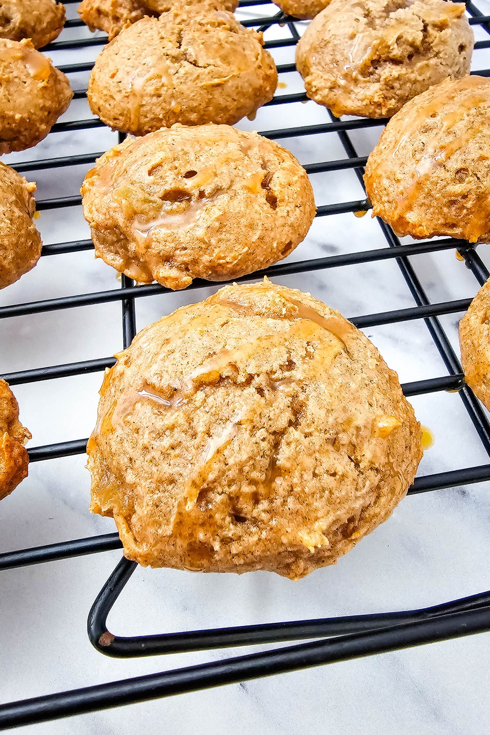 Soft apple pie filling cookies with caramel drizzle on a cooling rack