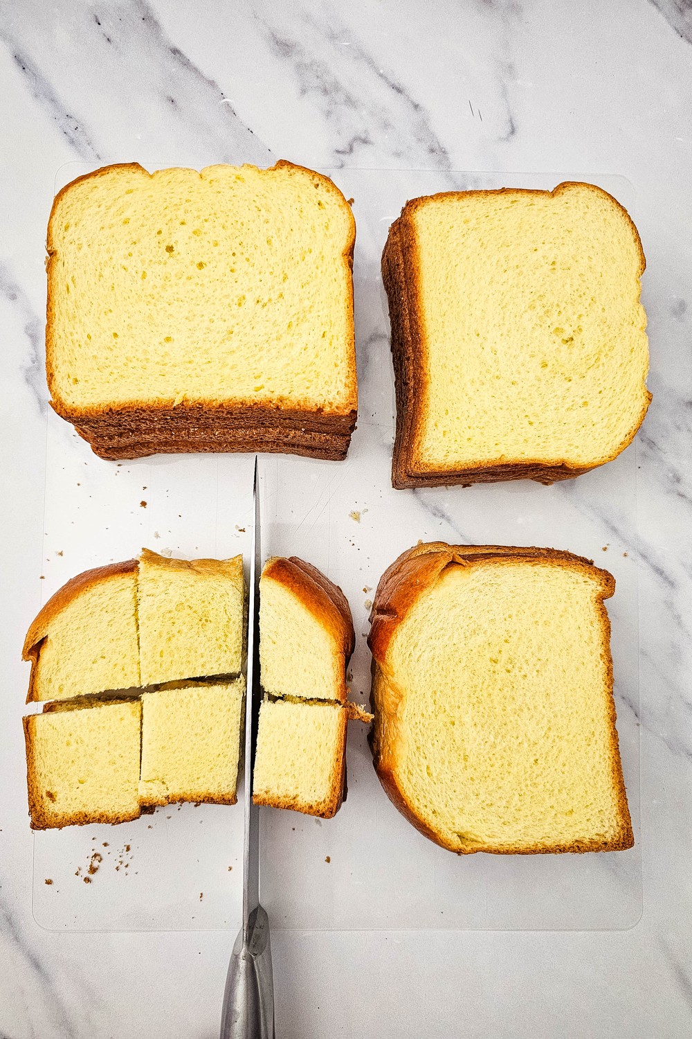 Cutting brioche bread slices into cubes on a cutting board