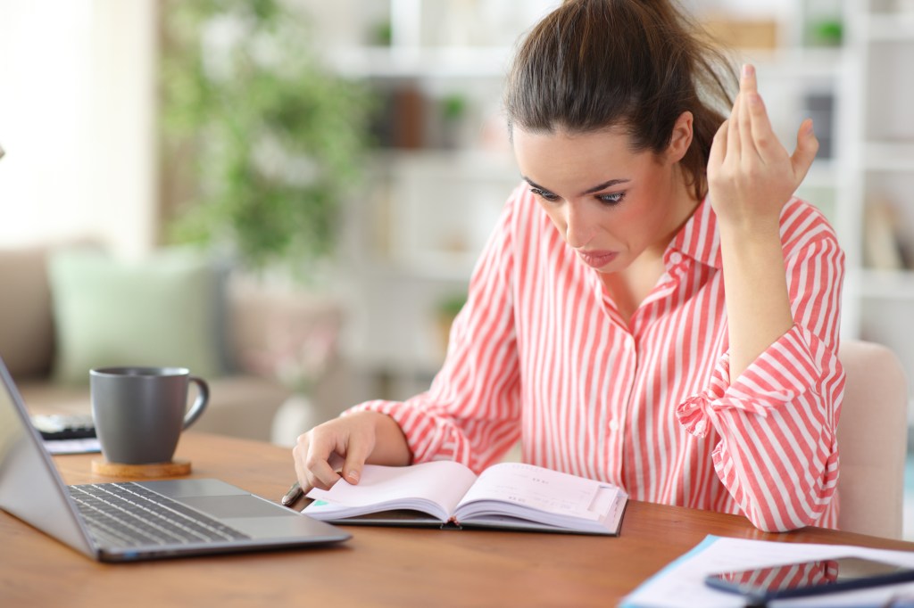 A woman appearing shocked while looking at a notebook.