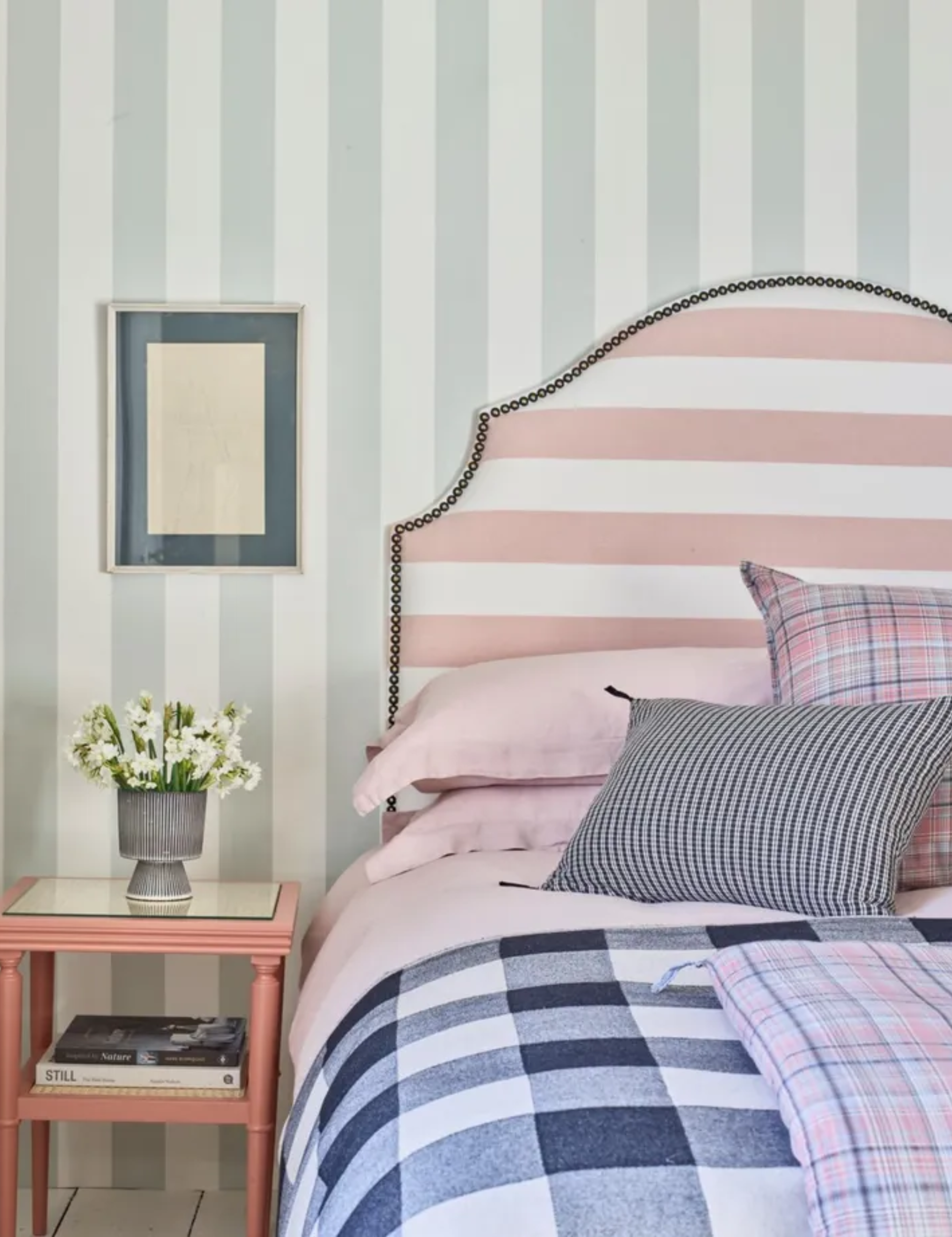 a bedroom with striped wallpaper, a striped headboard, and checker printed bedding