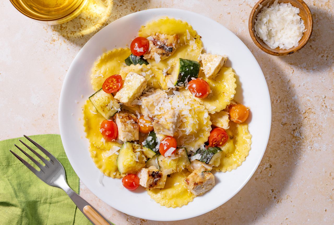 Plate of ravioli topped with vegetables and grated cheese