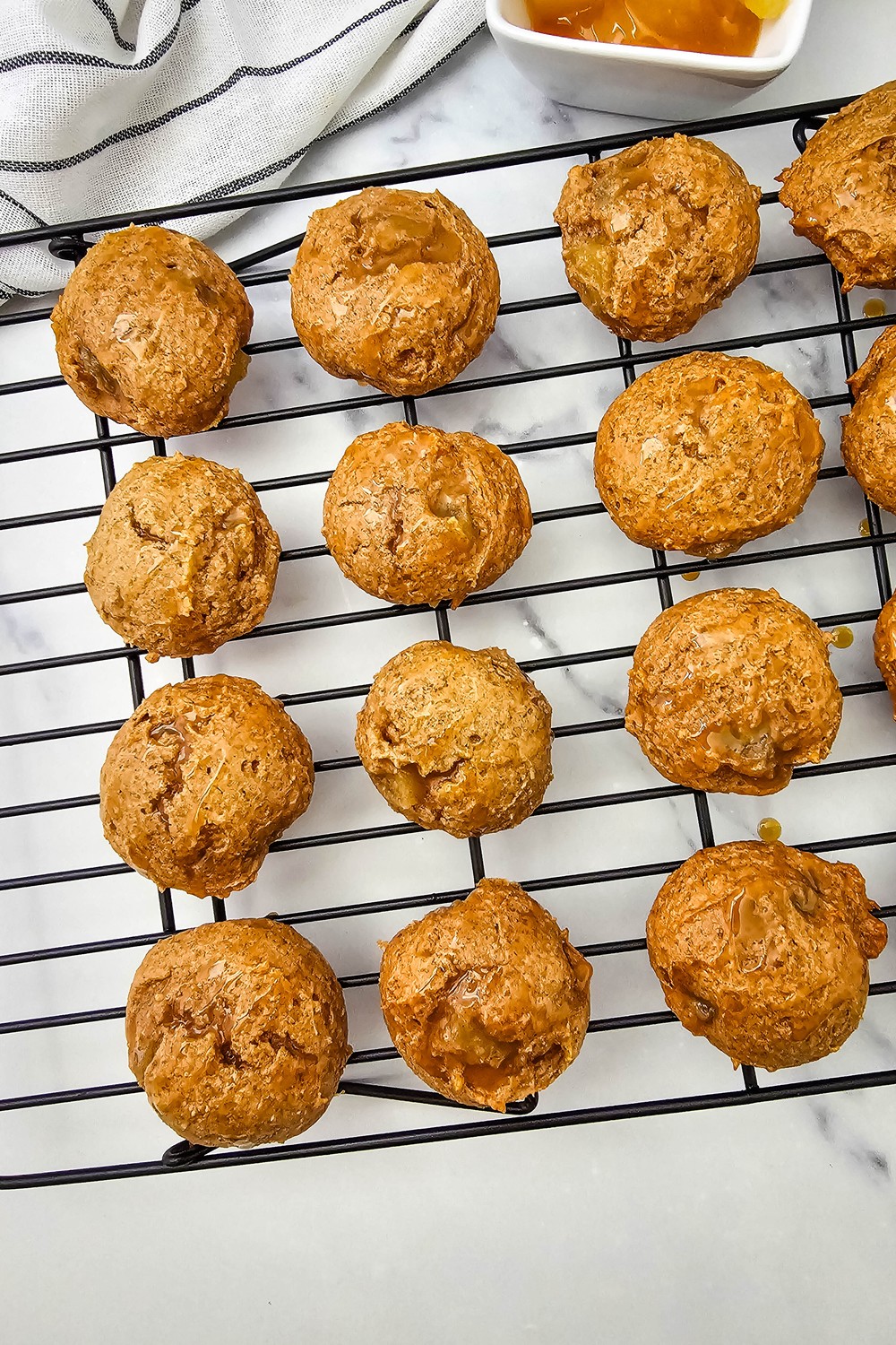 Overhead view of caramel drizzled apple pie filling cookies on a black wire cooling rack